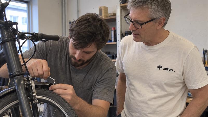 An Adfyo colleague talking with a bicycle repair shop owner